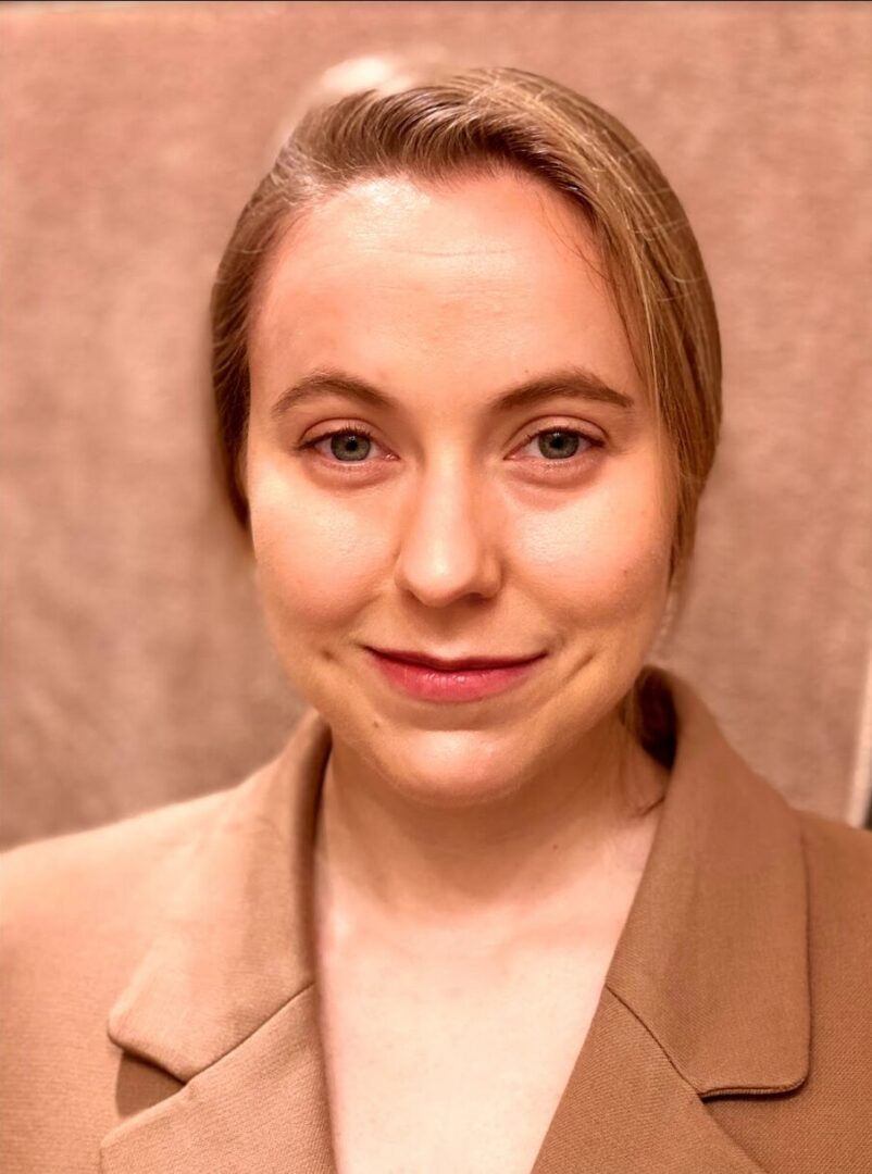 Person in brown coat, neutral expression.